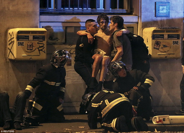 Các nhân viên cứu hỏa của Pháp giúp một người đàn ông bị thương đi khỏi hiện trường vụ tấn công khủng bố tại cuộc hòa nhạc Bataclan ở Paris đêm thứ sáu.