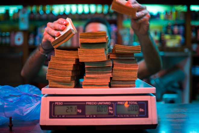 Thu ngân tại một cửa hàng bánh ở Venezuela đang cân tiền để bán hàng. Ảnh: Bloomberg.