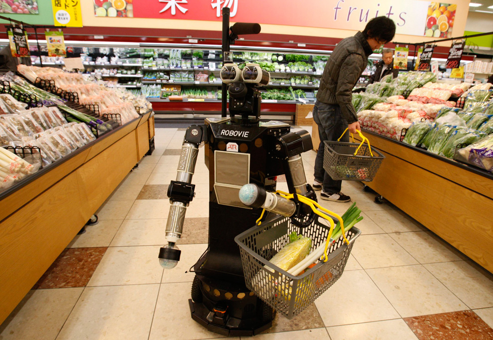 A robot named "Robovie-II", developed by Japanese robotics research institution ATR, moves around at a grocery store during a shopping assisting experiment by utilizing the robot in an ubiquitous network technology platform in Kyoto, western Japan January 6, 2010. The robot greets the shopper at the entrance of the store, follows him to the shelves while holding a grocery basket and reminds him of the items on a shopping list, which the shopper would have entered beforehand in a specialized mobile device. The experiment is aimed to gather data in order to provide livelihood support for the elderly by using robots and network technologies, ATR's researcher Satoshi Koizumi said. REUTERS/Yuriko Nakao (JAPAN - Tags: FOOD BUSINESS ODDLY SCI TECH IMAGES OF THE DAY SOCIETY)