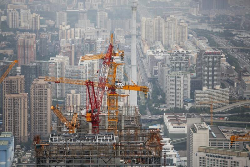 FILE PHOTO: Cranes are seen on top of a skyscraper that is under construction in Beijing, China August 26, 2017. REUTERS/Thomas Peter