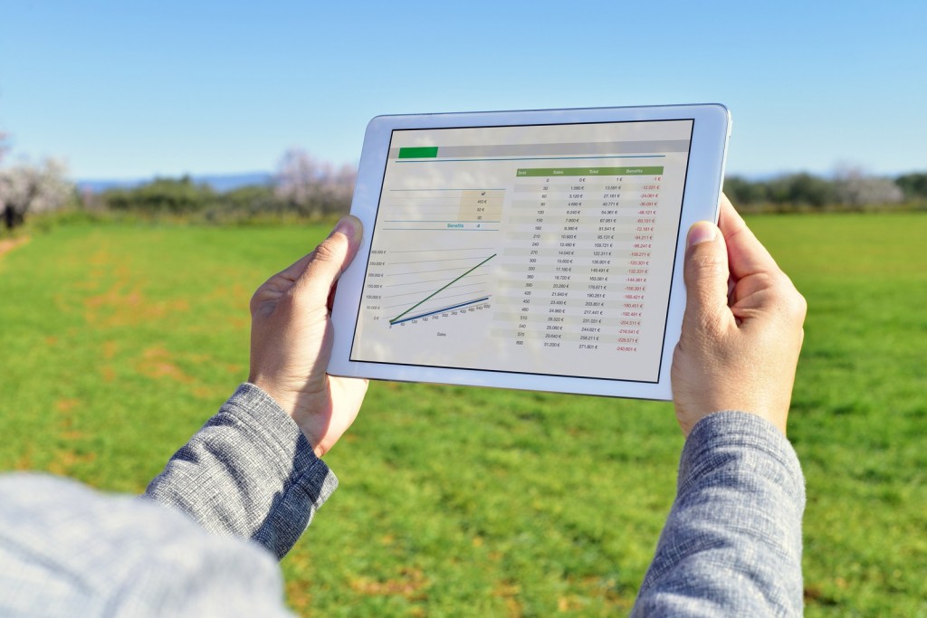 closeup of a young farmer observing some charts in a tablet computer in a fallow field